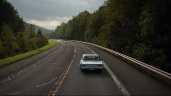 Movie still from “The Dead Don't Die” (2019), directed by Jim Jarmusch – A car driving down a road near some trees; Extreme Wide shot, High angle
