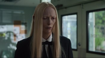 Movie still from “The Dead Don't Die” (2019), directed by Jim Jarmusch – A woman with long blonde hair wearing a suit and bow tie; Close Up shot, Over the shoulder angle