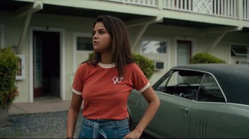 Movie still from “The Dead Don't Die” (2019), directed by Jim Jarmusch – A woman standing in front of a green car; Medium shot, Over the shoulder angle