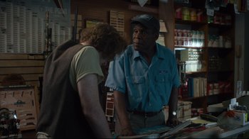 Movie still from “The Dead Don't Die” (2019), directed by Jim Jarmusch – A man standing in front of a counter with a woman; Medium shot, Over the shoulder angle