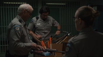 Movie still from “The Dead Don't Die” (2019), directed by Jim Jarmusch – A group of men standing around a table; Medium shot, Over the shoulder angle