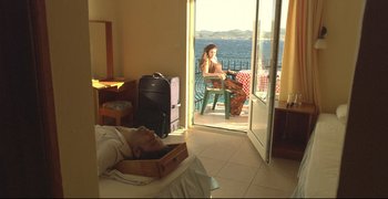 Movie still from “Climates” (2006), directed by Nuri Bilge Ceylan – A man laying in bed next to a woman in front of an open door; Wide shot, High angle