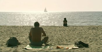 Movie still from “Climates” (2006), directed by Nuri Bilge Ceylan – A man and a woman sitting on the beach in front of the ocean; Extreme Wide shot, High angle