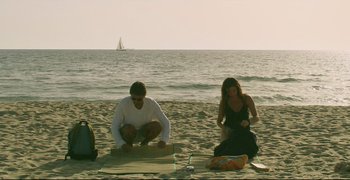 Movie still from “Climates” (2006), directed by Nuri Bilge Ceylan – A man and a woman sitting on the beach near the ocean; Wide shot, High angle