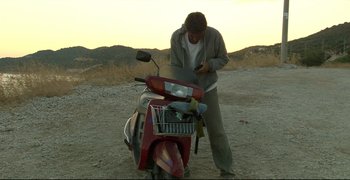Movie still from “Climates” (2006), directed by Nuri Bilge Ceylan – A man standing next to a parked motorcycle; Wide shot, High angle
