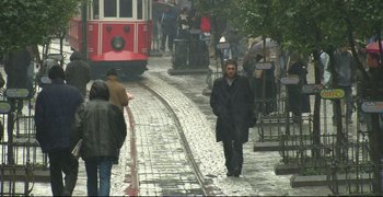 Movie still from “Climates” (2006), directed by Nuri Bilge Ceylan – A man walking down the street in the rain; Wide shot, High angle