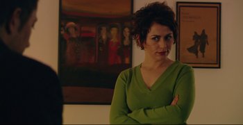 Movie still from “Climates” (2006), directed by Nuri Bilge Ceylan – A woman standing in front of a painting with her arms crossed; Close Up shot, Over the shoulder angle