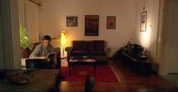 Movie still from “Climates” (2006), directed by Nuri Bilge Ceylan – A man sitting in a living room reading a book; Wide shot, High angle