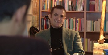 Movie still from “Climates” (2006), directed by Nuri Bilge Ceylan – A man sitting in front of a book shelf; Close Up shot, High angle