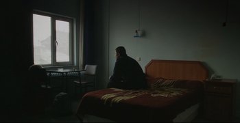 Movie still from “Climates” (2006), directed by Nuri Bilge Ceylan – A man sitting on a bed looking out the window; Wide shot, High angle