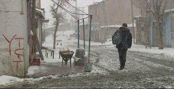 Movie still from “Climates” (2006), directed by Nuri Bilge Ceylan – A man walking down a street in the snow; Wide shot, Low angle