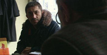 Movie still from “Climates” (2006), directed by Nuri Bilge Ceylan – A man wearing a jacket and a hood is sitting in front of a mirror; Close Up shot, Over the shoulder angle
