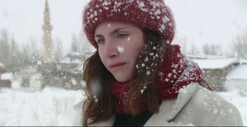 Movie still from “Climates” (2006), directed by Nuri Bilge Ceylan – A woman wearing a red hat and a red scarf in the snow; Close Up shot, Low angle