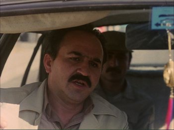 Movie still from “Close-Up” (1990), directed by Abbas Kiarostami – A man with a mustache in the back of a car; Close Up shot, Low angle