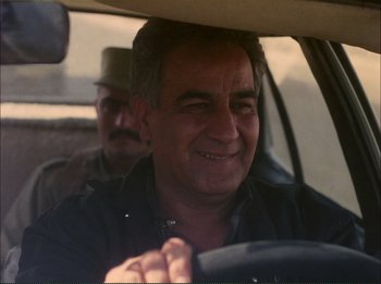 Movie still from “Close-Up” (1990), directed by Abbas Kiarostami – A man driving a car while another man looks on; Close Up shot, Over the shoulder angle