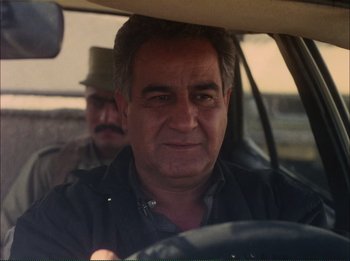 Movie still from “Close-Up” (1990), directed by Abbas Kiarostami – A man sitting in the drivers seat of a car; Close Up shot, Over the shoulder angle
