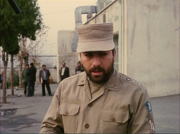 Movie still from “Close-Up” (1990), directed by Abbas Kiarostami – A man in a uniform is standing in front of a building; Medium shot, Over the shoulder angle