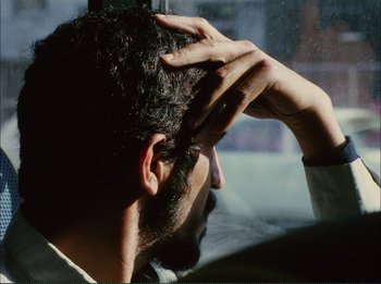 Movie still from “Close-Up” (1990), directed by Abbas Kiarostami – A person holding his hand up to his head; Close Up shot, Over the shoulder angle
