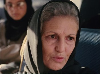 Movie still from “Close-Up” (1990), directed by Abbas Kiarostami – An older woman wearing a head scarf and looking at the camera; Close Up shot, Low angle