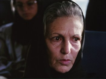 Movie still from “Close-Up” (1990), directed by Abbas Kiarostami – An older woman wearing a head covering looking at the camera; Close Up shot, Over the shoulder angle