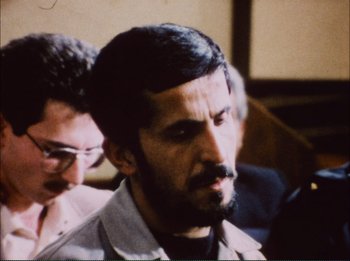 Movie still from “Close-Up” (1990), directed by Abbas Kiarostami – A man with a goatee is looking at the camera; Close Up shot, Over the shoulder angle