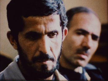 Movie still from “Close-Up” (1990), directed by Abbas Kiarostami – A man with a beard and mustache and another man with a beard and mustache; Close Up shot, Over the shoulder angle