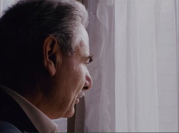 Movie still from “Close-Up” (1990), directed by Abbas Kiarostami – An older man looking out of a window; Close Up shot, Low angle