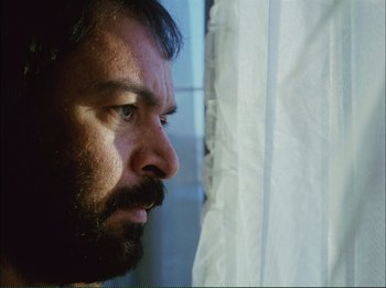 Movie still from “Close-Up” (1990), directed by Abbas Kiarostami – A man with a beard looking out of a window; Close Up shot, Low angle