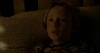 Movie still from “Closet Monster” (2015), directed by Stephen Dunn – A little boy sitting on a couch in the dark; Close Up shot, High angle