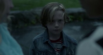 Movie still from “Closet Monster” (2015), directed by Stephen Dunn – A young boy in a jean jacket looking at the camera; Close Up shot, Over the shoulder angle