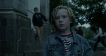 Movie still from “Closet Monster” (2015), directed by Stephen Dunn – A young boy standing next to a staircase; Close Up shot, Over the shoulder angle