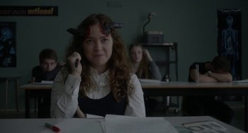 Movie still from “Closet Monster” (2015), directed by Stephen Dunn – A woman sitting at a table with a phone in her hand; Close Up shot, High angle