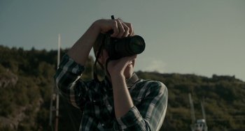 Movie still from “Closet Monster” (2015), directed by Stephen Dunn – A man holding a camera up to his face; Extreme Close Up shot, Low angle