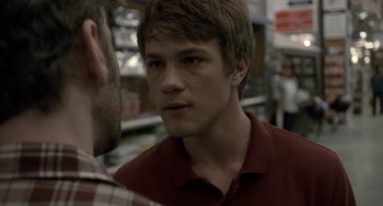 Movie still from “Closet Monster” (2015), directed by Stephen Dunn – A man in a red shirt is talking to another man in a plaid shirt; Close Up shot, Over the shoulder angle