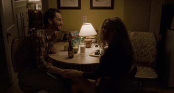 Movie still from “Closet Monster” (2015), directed by Stephen Dunn – A man and a woman sitting at a dinner table; Medium shot, High angle