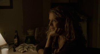 Movie still from “Closet Monster” (2015), directed by Stephen Dunn – A woman sitting at a table in a dark room; Close Up shot, Over the shoulder angle