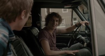 Movie still from “Closet Monster” (2015), directed by Stephen Dunn – A man sitting in the driver's seat of a car; Medium shot, Over the shoulder angle