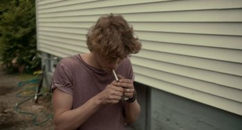 Movie still from “Closet Monster” (2015), directed by Stephen Dunn – A young man holding a cigarette in his mouth; Medium shot, High angle