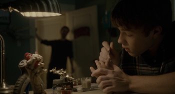 Movie still from “Closet Monster” (2015), directed by Stephen Dunn – A man sitting at a table with a glass of wine; Medium shot, Over the shoulder angle