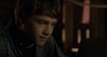 Movie still from “Closet Monster” (2015), directed by Stephen Dunn – A young man is looking down at a laptop; Close Up shot, Over the shoulder angle