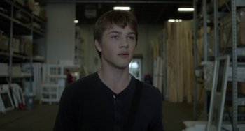 Movie still from “Closet Monster” (2015), directed by Stephen Dunn – A young man is standing in a warehouse; Close Up shot, Over the shoulder angle