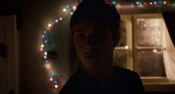 Movie still from “Closet Monster” (2015), directed by Stephen Dunn – A young man standing in front of christmas lights; Close Up shot, Over the shoulder angle