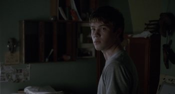 Movie still from “Closet Monster” (2015), directed by Stephen Dunn – A young man standing in front of a book shelf; Close Up shot, Over the shoulder angle
