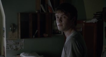 Movie still from “Closet Monster” (2015), directed by Stephen Dunn – A young man is smiling for the camera; Close Up shot, Over the shoulder angle