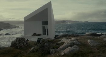 Movie still from “Closet Monster” (2015), directed by Stephen Dunn – A house sitting next to a body of water; Extreme Wide shot, Low angle