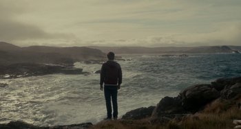 Movie still from “Closet Monster” (2015), directed by Stephen Dunn – A man standing on top of a cliff looking out at the ocean; Extreme Wide shot, Over the shoulder angle