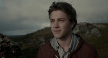 Movie still from “Closet Monster” (2015), directed by Stephen Dunn – A man in a red jacket is looking at the camera; Close Up shot, Over the shoulder angle