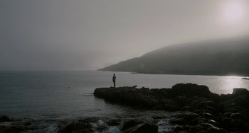 Movie still from “Closet Monster” (2015), directed by Stephen Dunn – A man standing on a rock in the water; Extreme Wide shot, Low angle
