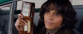 Movie still from “Cloud Atlas” (2012), directed by Lilly Wachowski – A woman holding a wallet with her passport in front of her face; Close Up shot, High angle