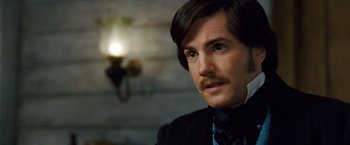 Movie still from “Cloud Atlas” (2012), directed by Lilly Wachowski – A person wearing a suit and tie; Close Up shot, Over the shoulder angle